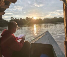 2025 Peru - Fr. Romulo Oliva prays while traveling by boat during his missionary trip.